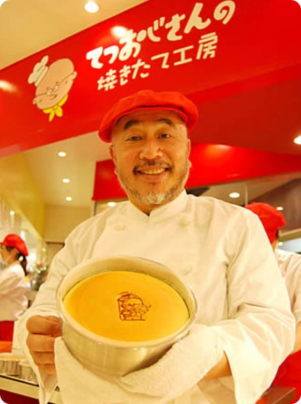 Tetsushi Mizokami, the real Uncle Tetsu, smiling and holding a Japanese cheesecake